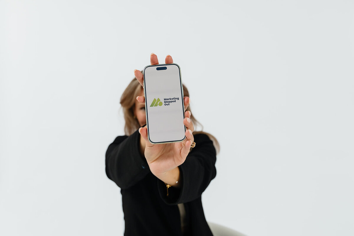 Alex holding a phone showing Marketing Mapped Out